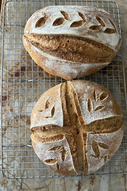 Two round country sourdough loaves centered on a cooling rack